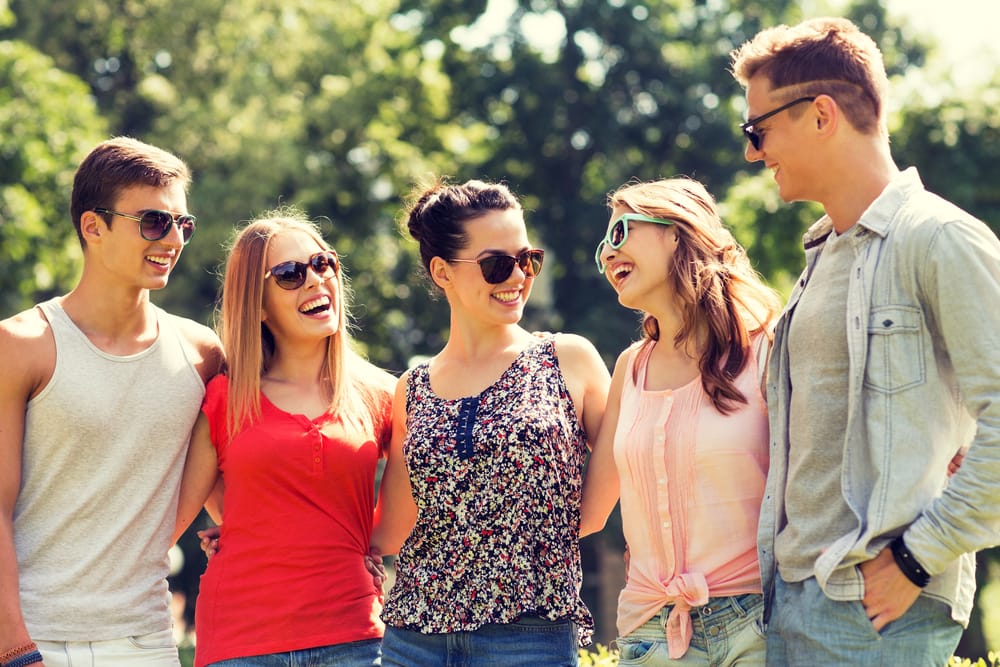 Stylish Shades and Summer Smiles – Eyeland Eyecare A group of five young adults wearing sunglasses and smiling together outdoors on a sunny day – Eyeland Eyecare.